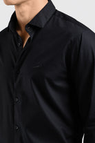 Close-up of a black shirt with a collar and buttons on a light gray background
