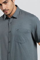 Man wearing a gray short-sleeve shirt with a pocket on a white background