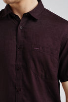 Close-up of a maroon button-up shirt with a pocket on a plain background
