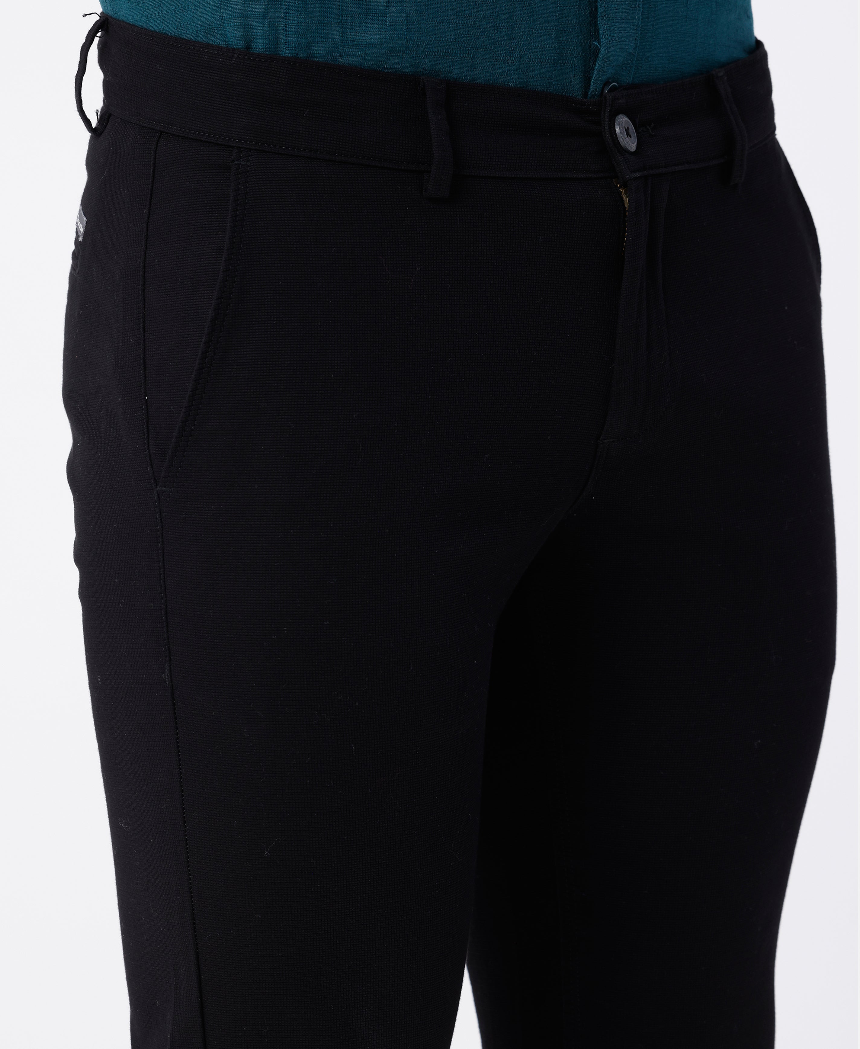 Woman wearing a black textured essential chinos in black on a light gray background