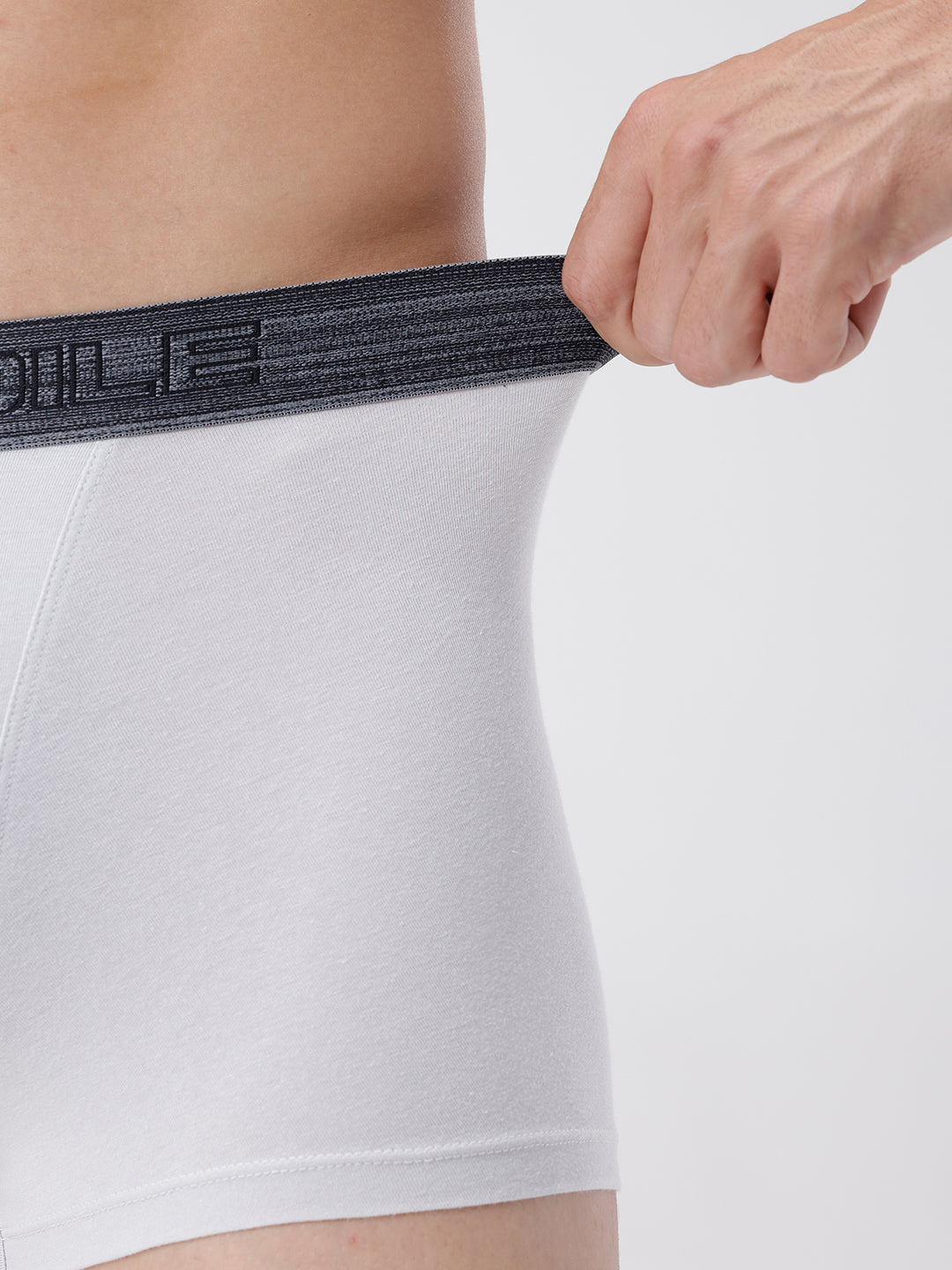 Person wearing a white athletic shirt with a black waistband, holding the waistband.