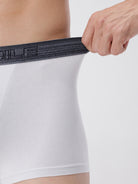 Person wearing a white athletic shirt with a black waistband, holding the waistband.