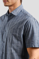 Close-up of a person wearing a blue striped shirt with a pocket on a gray background
