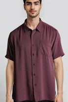 Man wearing a maroon short-sleeve shirt against a plain background