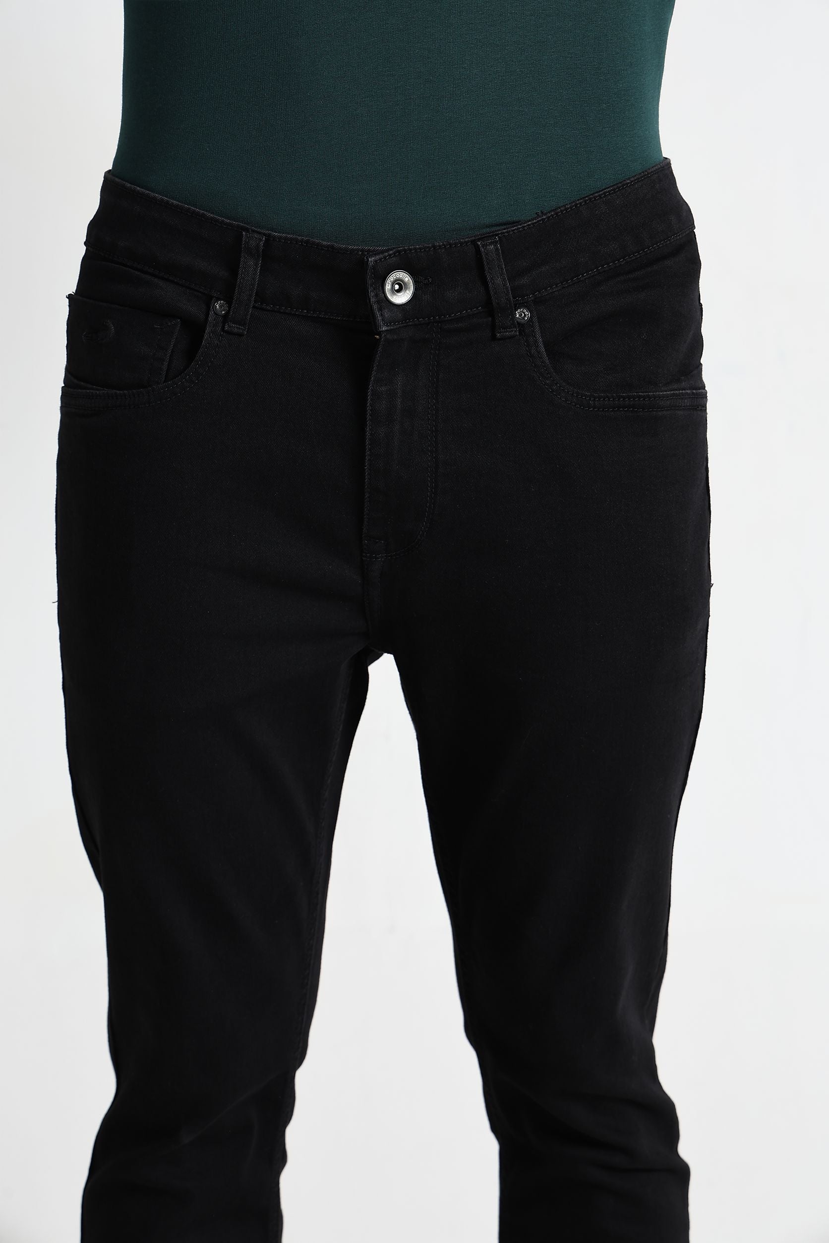 Black jeans worn over a green top on a white background