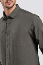 Man wearing a dark gray button-up shirt on a light gray background