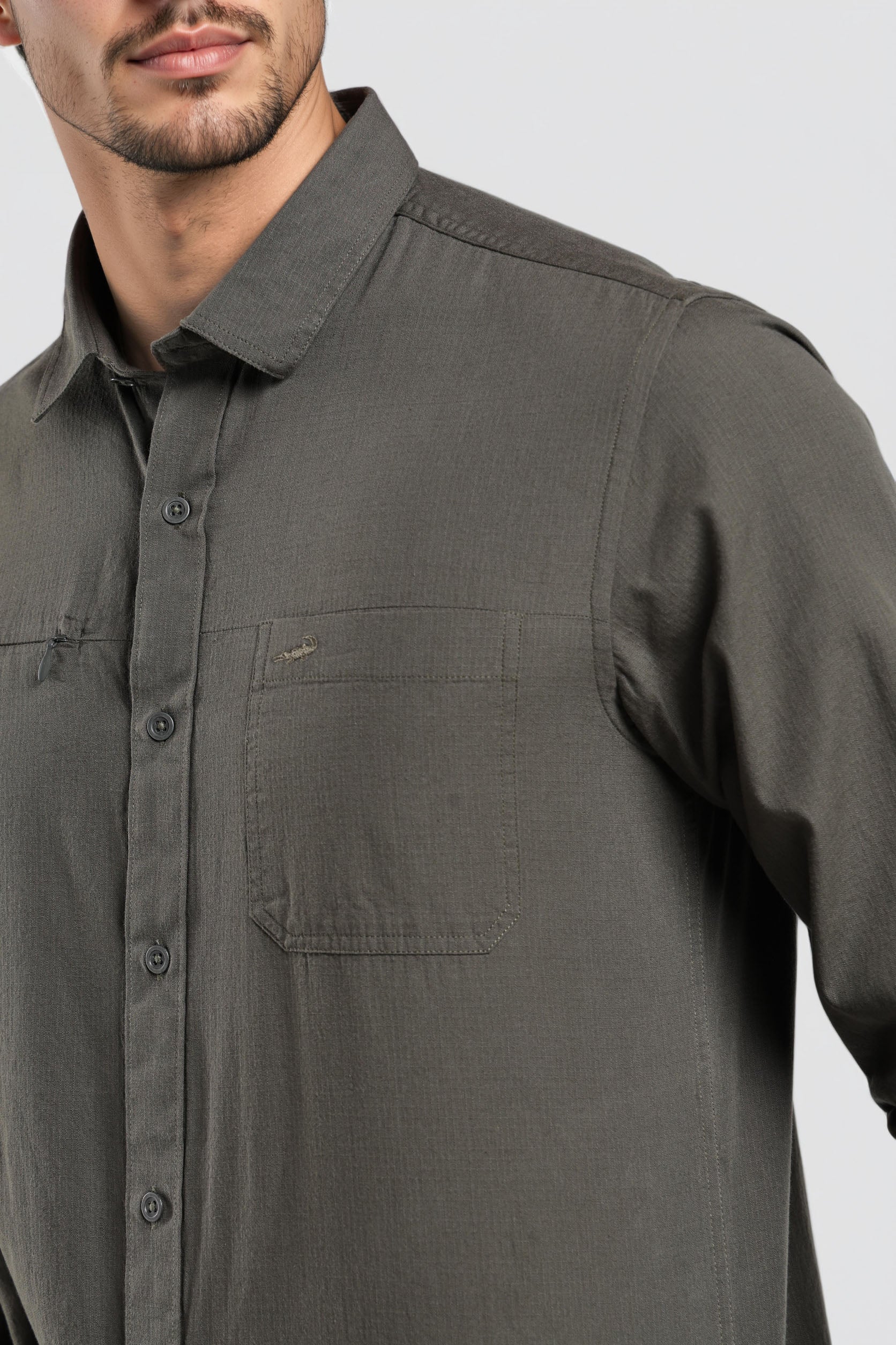 Man wearing a dark gray button-up shirt on a light gray background