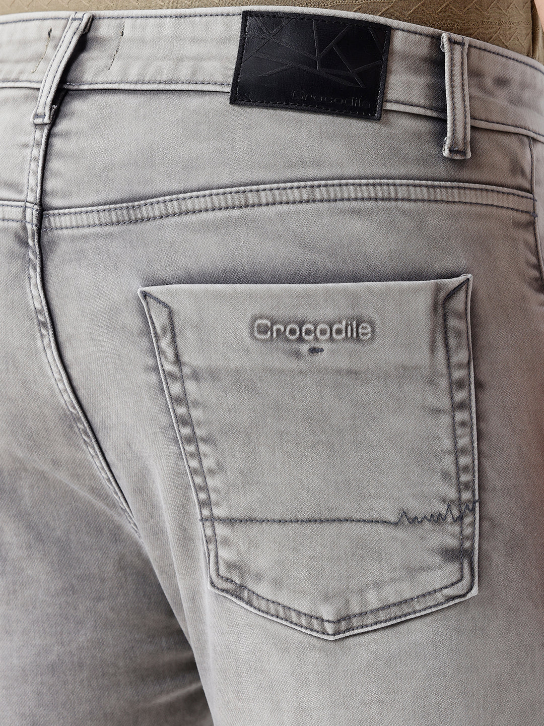 Man wearing a grey light grey knit slim fit jeans on a light gray background