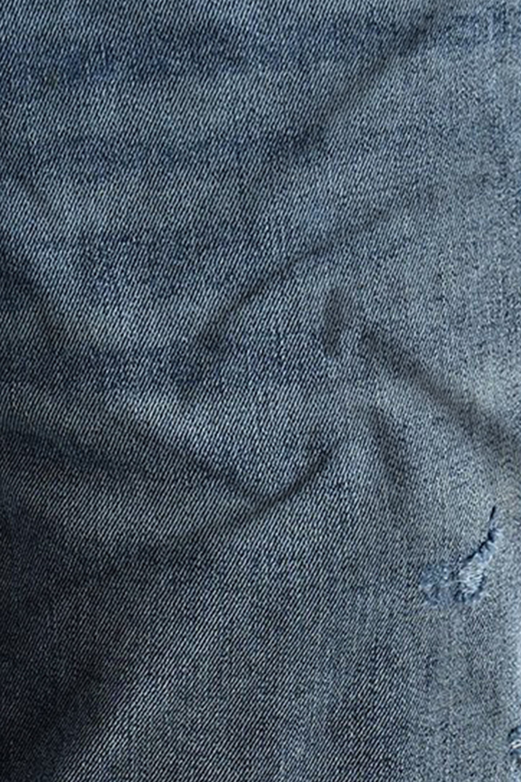 Close-up of dark blue denim fabric with texture and slight wear.