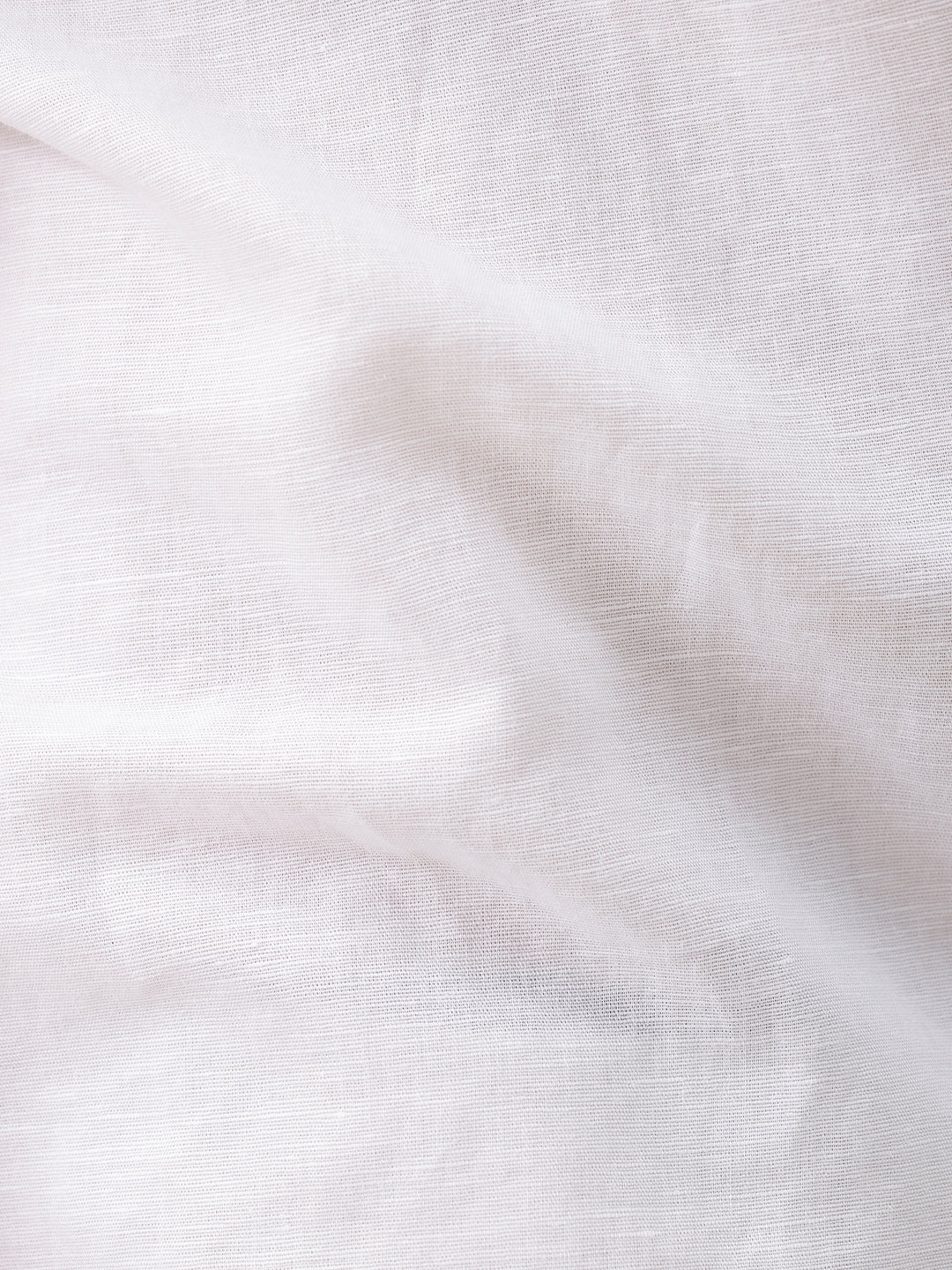 A man wearing a white short-sleeve button-up shirt with a chest pocket and beige trousers, standing against a plain white studio background.