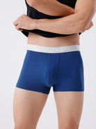 Blue boxer briefs with a white waistband featuring a brand logo on a plain background