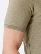 Man wearing a olive light olive structure comfort fit polo t shirt on a light gray background