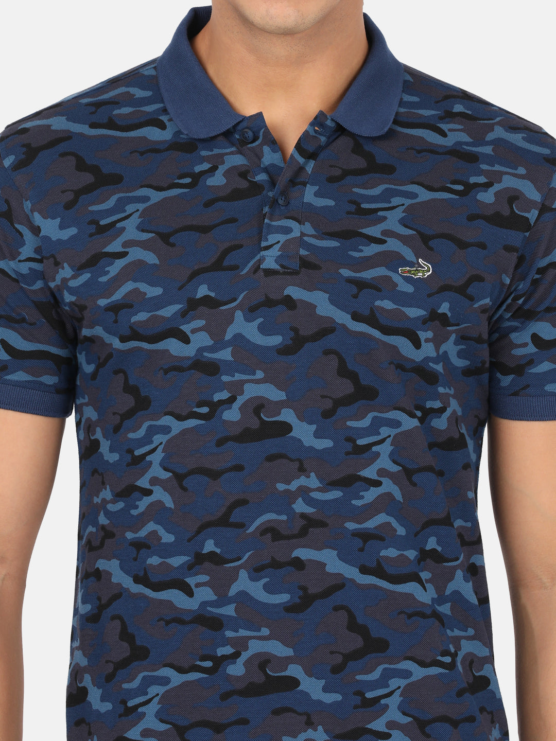 Man wearing a blue royal blue printed polo t shirt with casual styling on a gray background