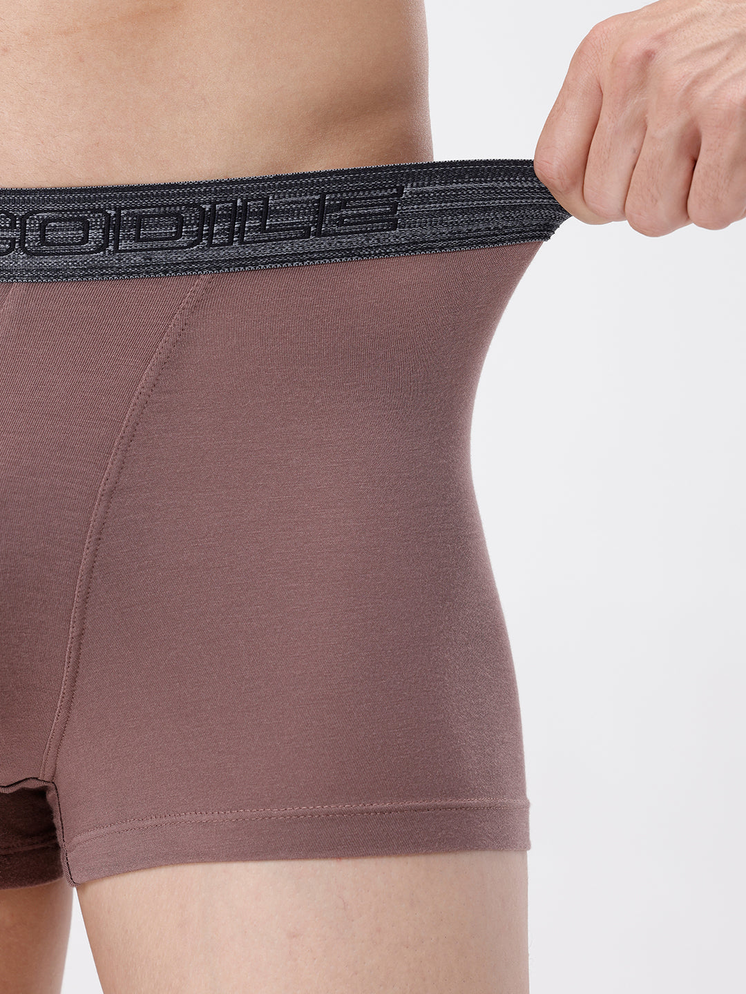 Brown boxer briefs with black waistband held by a hand on a white background