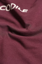 Close-up of a maroon fabric with 'CODILE' embroidered in white.