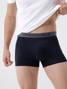 Person wearing black boxer briefs with a brand logo on a white background