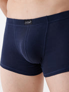 Navy blue boxer briefs with a brand label on a neutral background
