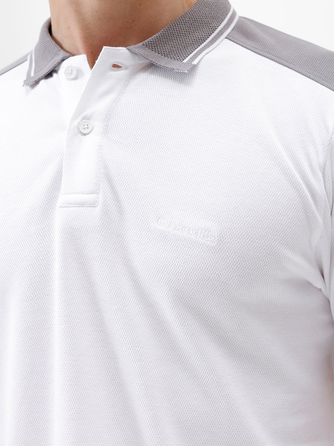 A man modeling a white short-sleeve polo shirt with gray shoulder panels and gray striped trim on the sleeves, paired with gray trousers and black sunglasses, against a plain white background.