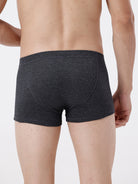 Person wearing dark gray boxer briefs on a plain background
