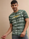 Man wearing a green kombu green tie and dye slim fit t shirt with casual styling on a gray background