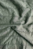 Close-up of textured green fabric with a subtle pattern