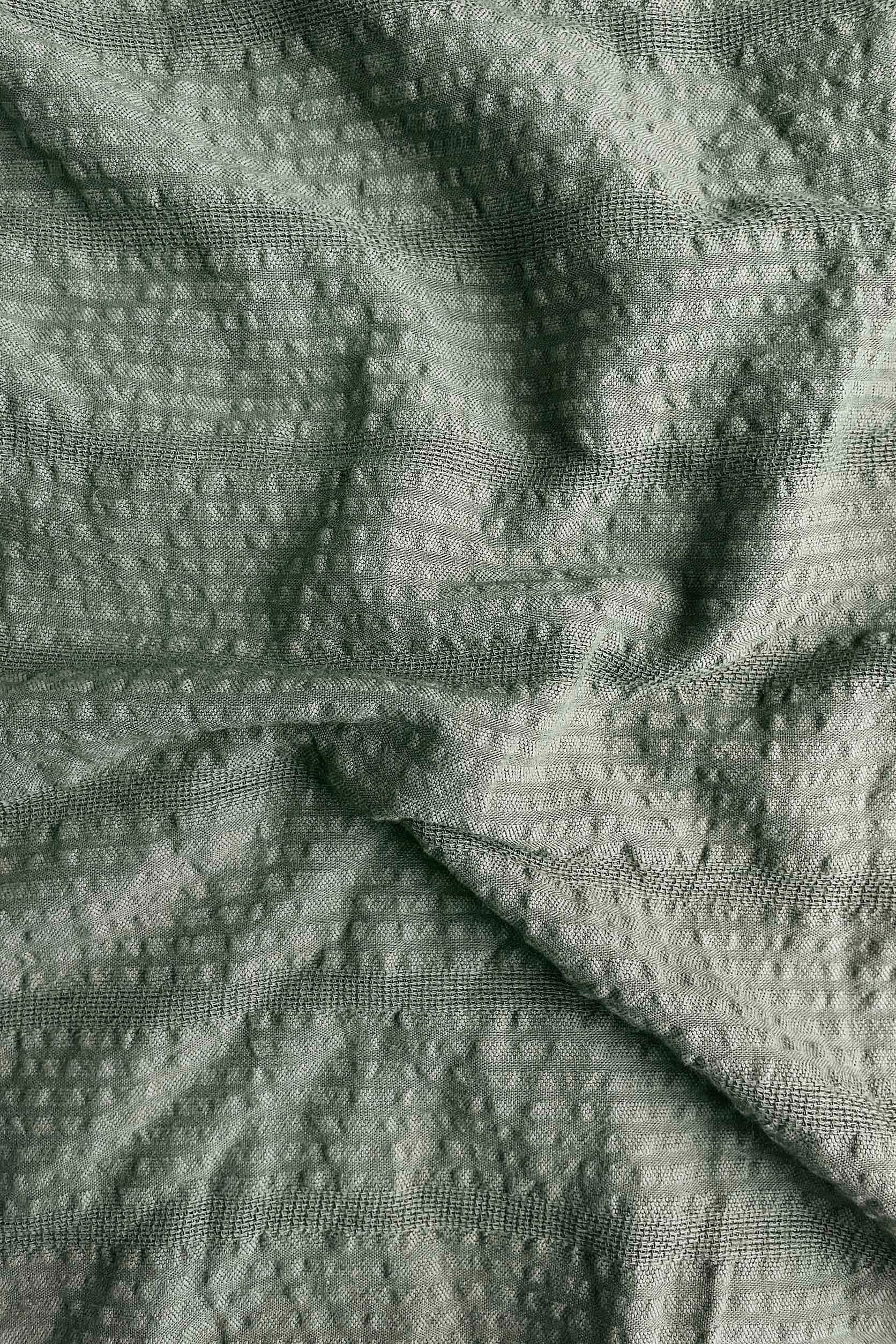 Close-up of textured green fabric with a subtle pattern