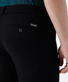 Woman wearing a black textured essential chinos in black on a light gray background