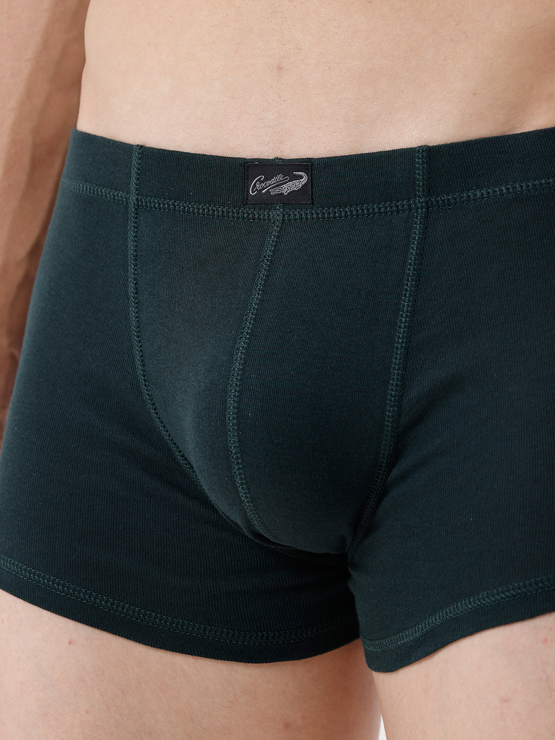 Dark green boxer briefs with a brand label on a beige background