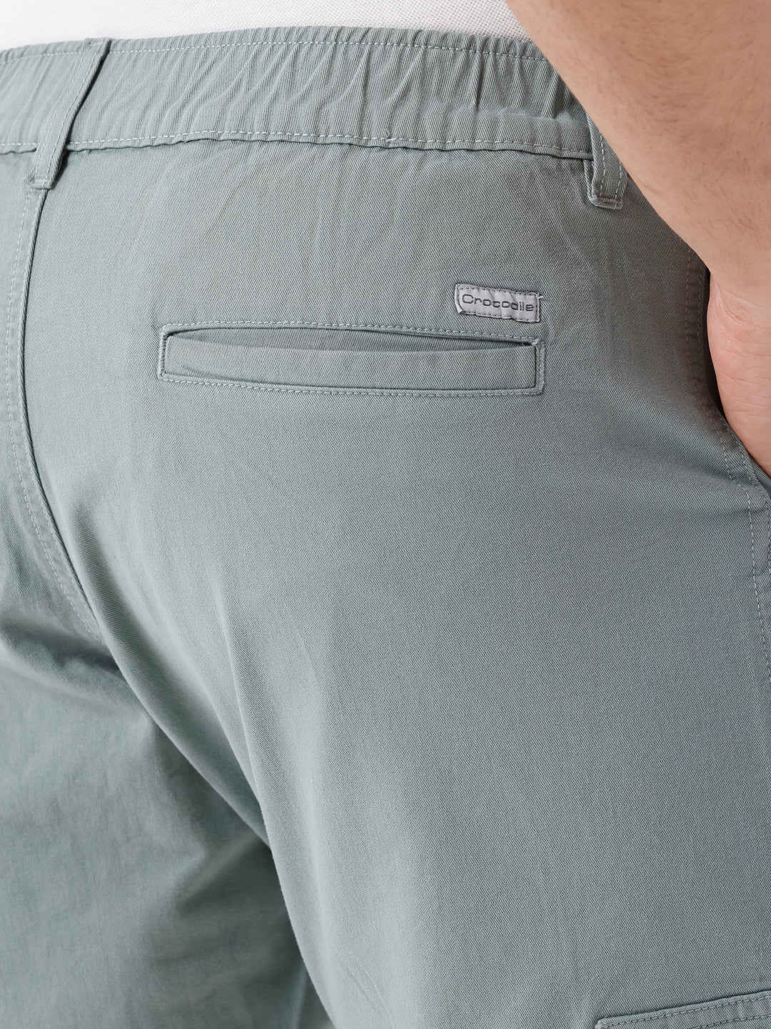 Man wearing a olive garment dyed cargo shorts in olive on a light gray background