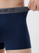 Navy blue boxer briefs with a brand logo on the waistband against a light gray background