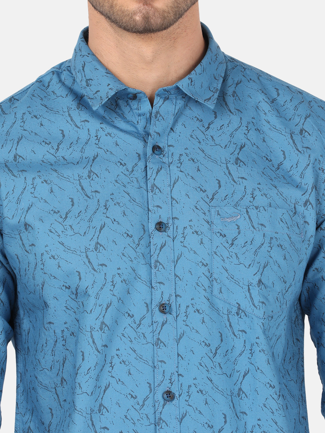 Man wearing a blue river blue printed full sleeve shirt on a light gray background