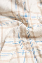 Close-up of checkered fabric with blue lines on a beige background