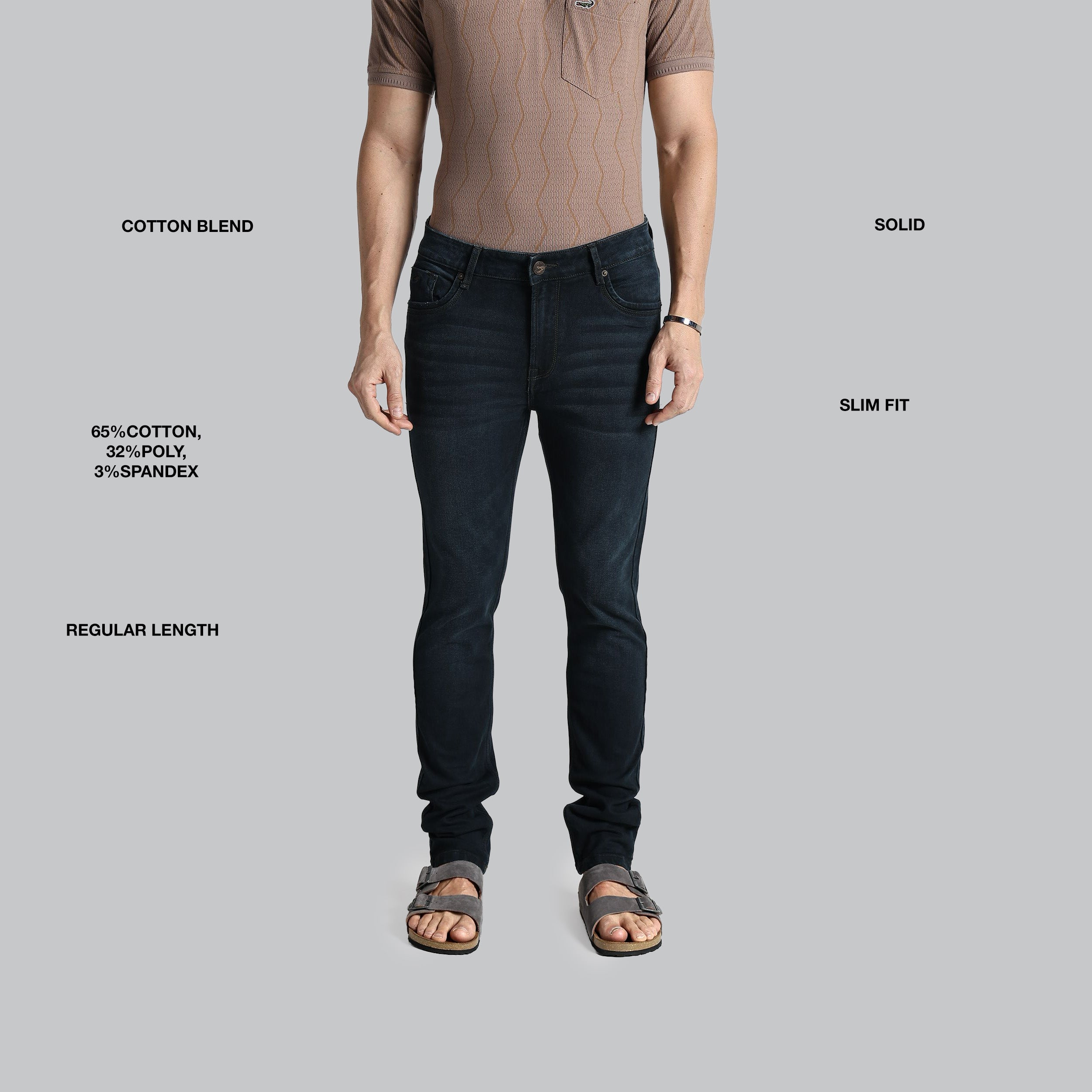 Man wearing black jeans with text detailing fabric composition, fit, and length on a gray background