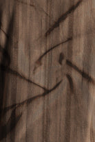 Close-up of a textured brown fabric with dark brown abstract patterns.