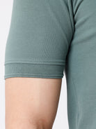 Man wearing a green iceberg green chest print slim fit polo t shirt on a light gray background