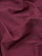 A man wearing a short-sleeve polo shirt in maroon with gray sleeve trim and a half-zip collar, paired with beige cargo pants, against a plain white studio background.