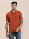 Man wearing a brown bombay brown solid polo t shirt with casual styling on a gray background