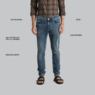 Person wearing blue jeans with text detailing fabric blend, length, and style on a gray background