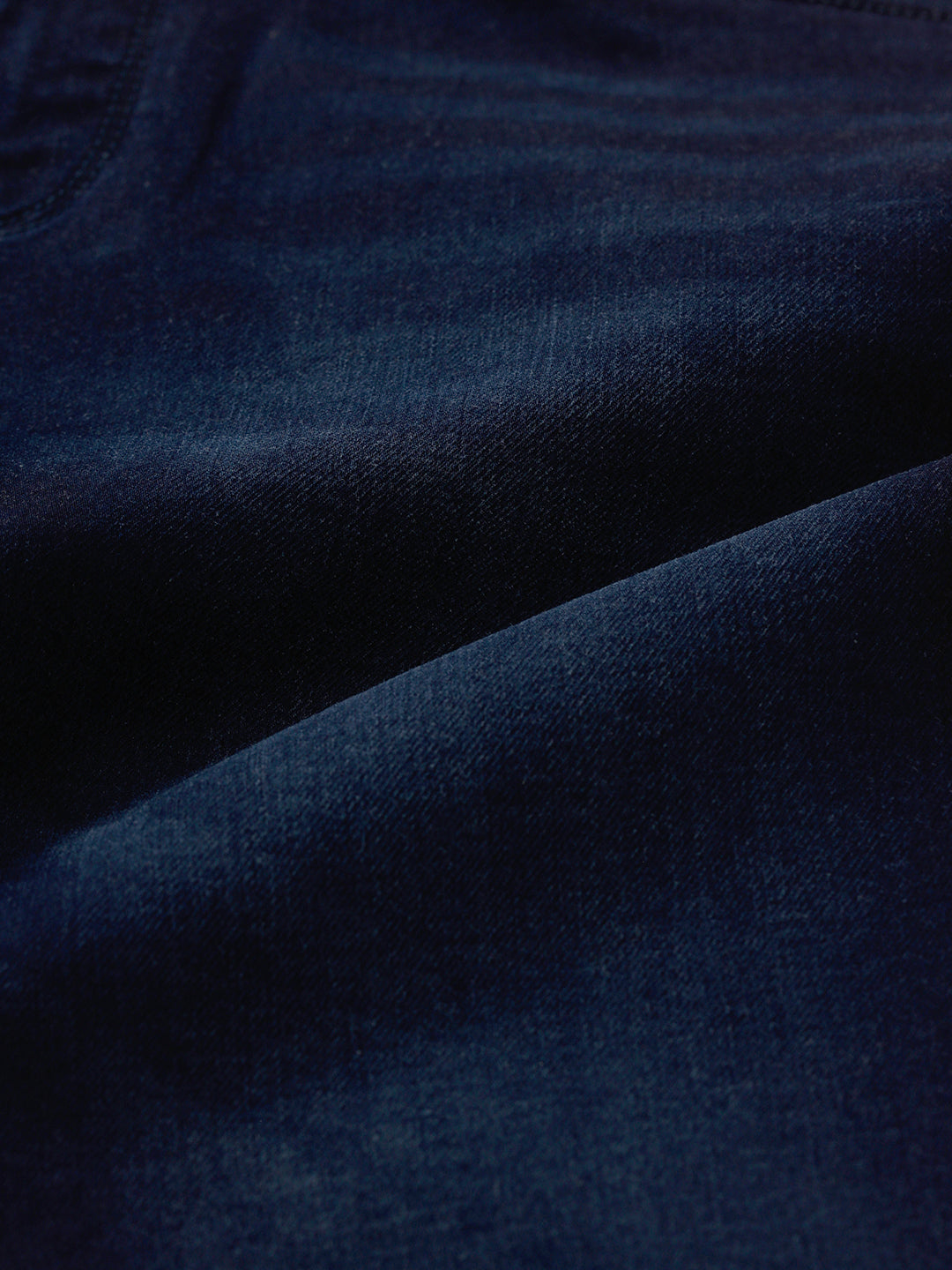 Man wearing a blue dark blue knit slim fit jeans with casual styling on a gray background