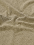 Man wearing a olive light olive structure comfort fit polo t shirt on a light gray background