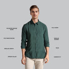 Man wearing a green shirt with text detailing fabric blend, sleeve length, and other features on a gray background