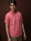 Man wearing a red mineral red solid half sleeve linen shirt on a light gray background
