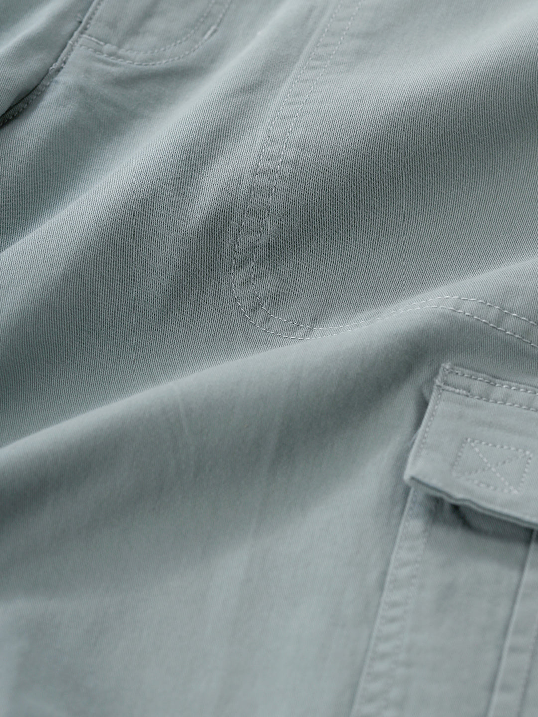 Man wearing a olive garment dyed cargo shorts in olive on a light gray background