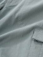 Man wearing a olive garment dyed cargo shorts in olive on a light gray background