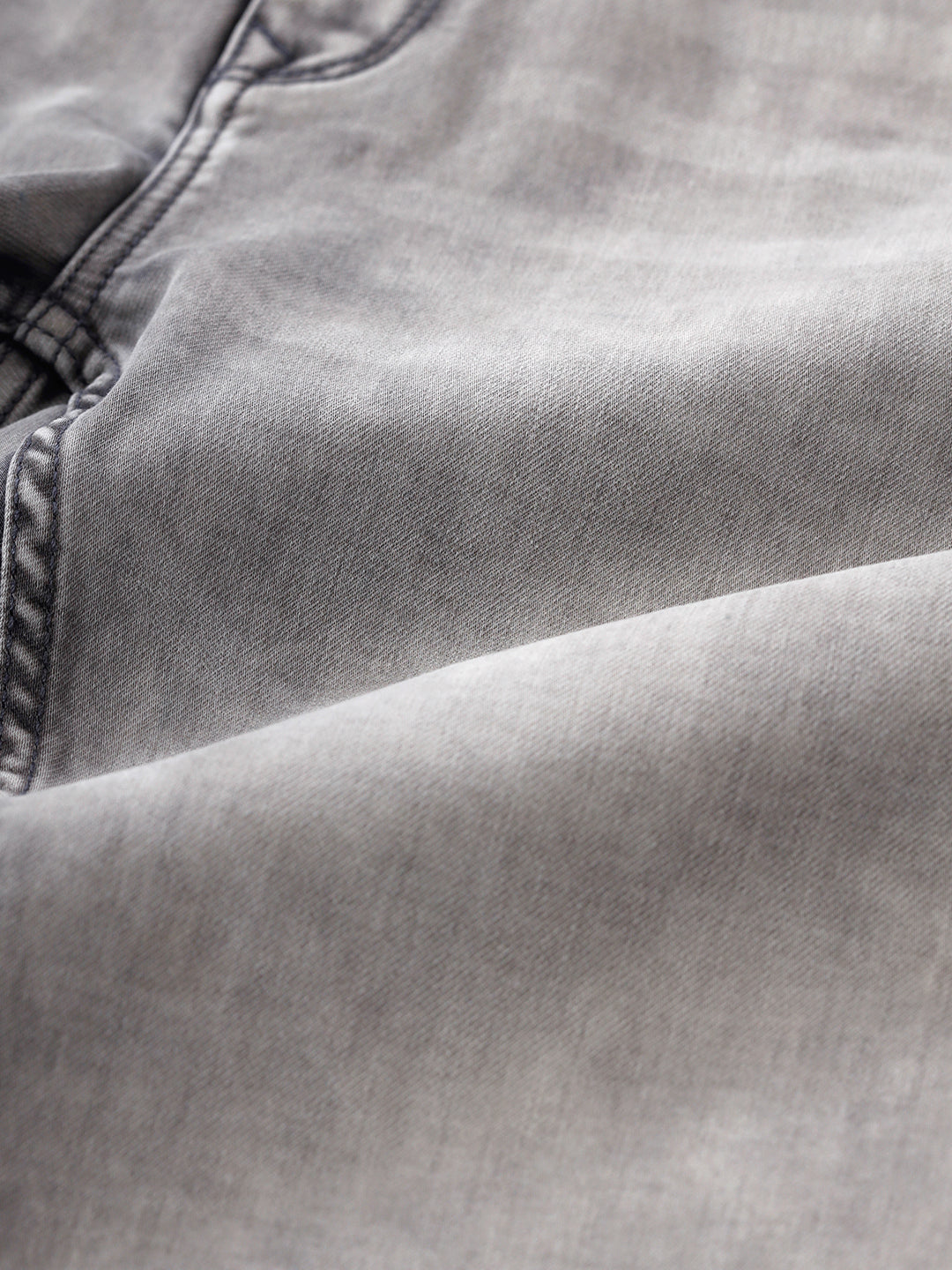 Man wearing a grey light grey knit slim fit jeans on a light gray background