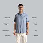 Man wearing a light blue shirt with text describing fabric blend, sleeve length, and other details on a gray background