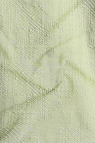 Close-up of a textured light green fabric with a subtle pattern
