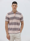A man wearing a short-sleeve polo shirt with horizontal stripes in dusty pink and gray, paired with light beige trousers, against a plain light gray background.