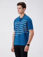 Man wearing a green iceberg green chest print slim fit polo t shirt on a light gray background