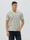 A man wearing a short-sleeve polo shirt with a beige and gray geometric pattern, paired with dark blue jeans, standing against a light gray background.